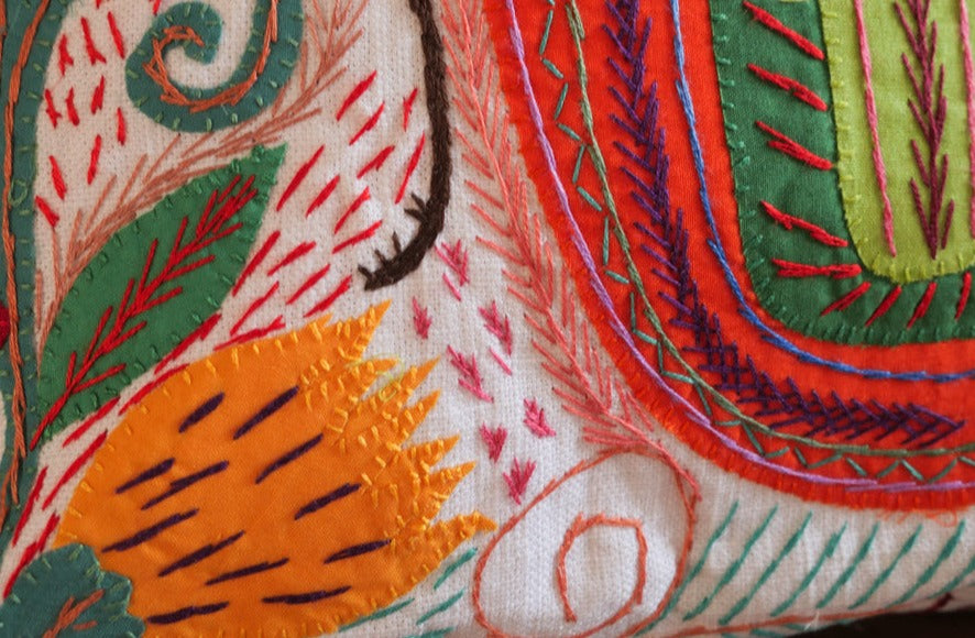 Coussin brode main avec des motifs insectes et fleur, commerce equitable.
